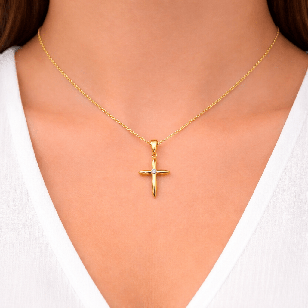 Hängsmycke kors i 18k guld. Litet stilrent kors med en gnistande cubic zirkonia kristall i mitten på kunds hals