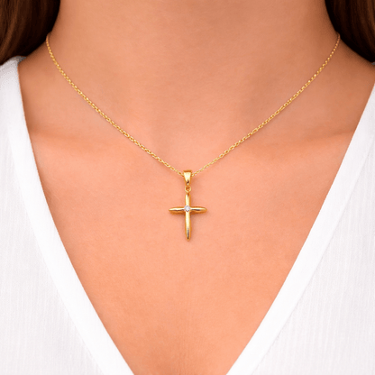 Hängsmycke kors i 18k guld. Litet stilrent kors med en gnistande cubic zirkonia kristall i mitten på kunds hals