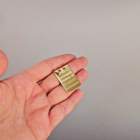 Eliquis bricka i äkta silver med guld förgyllning, med text på svenska och engelska på andra sidan.